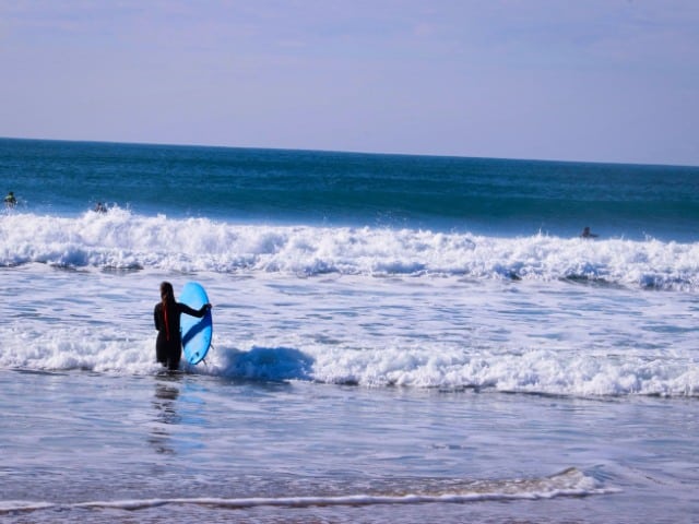 Jovem entrando no mar de costa de caparica com sua prancha de surf